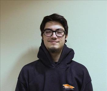 A man with dark hair and glasses wearing a black SERVPRO hoodie
