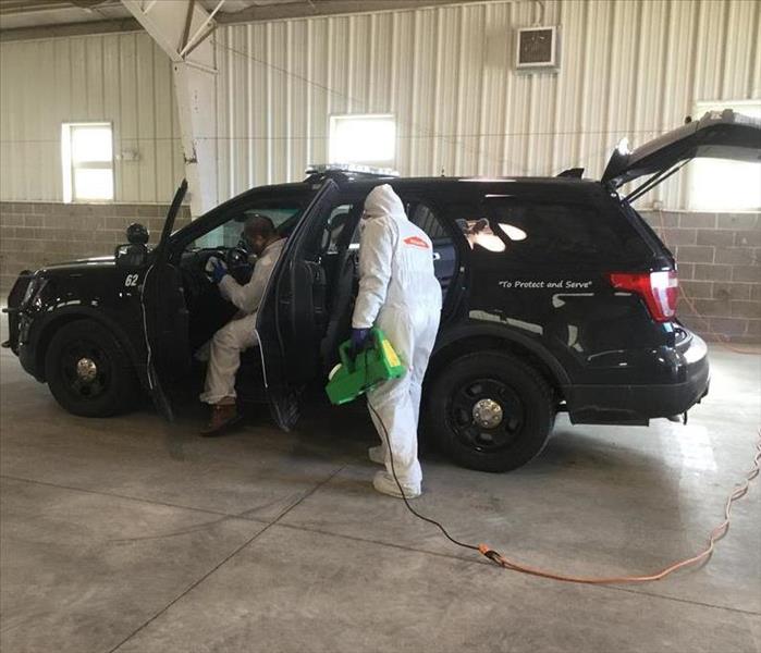 2 SERVPRO technicians cleaning and disinfecting a police vehicle