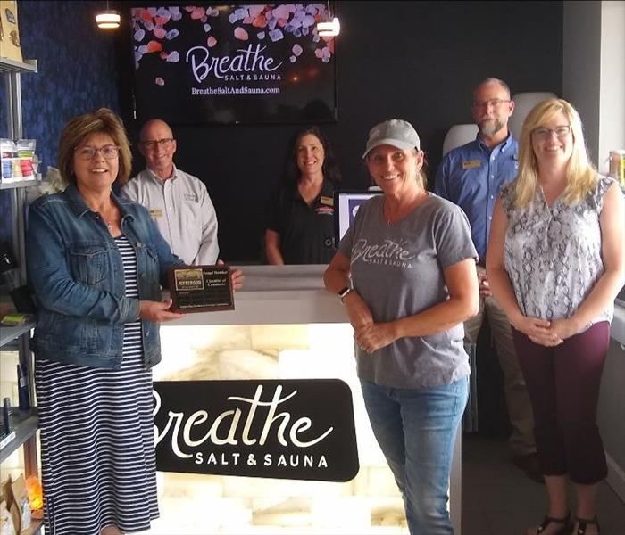 Group of People welcoming a new chamber member who is holding a plaque
