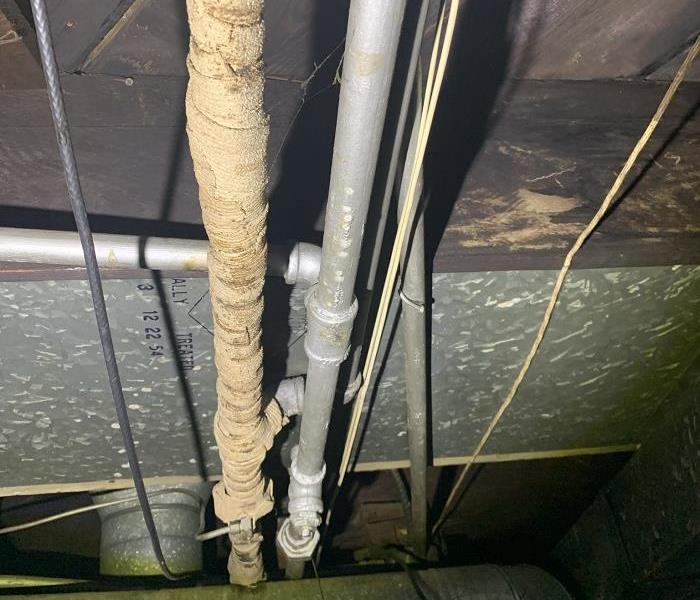 Pipes hanging from ceiling wrapped with insulation