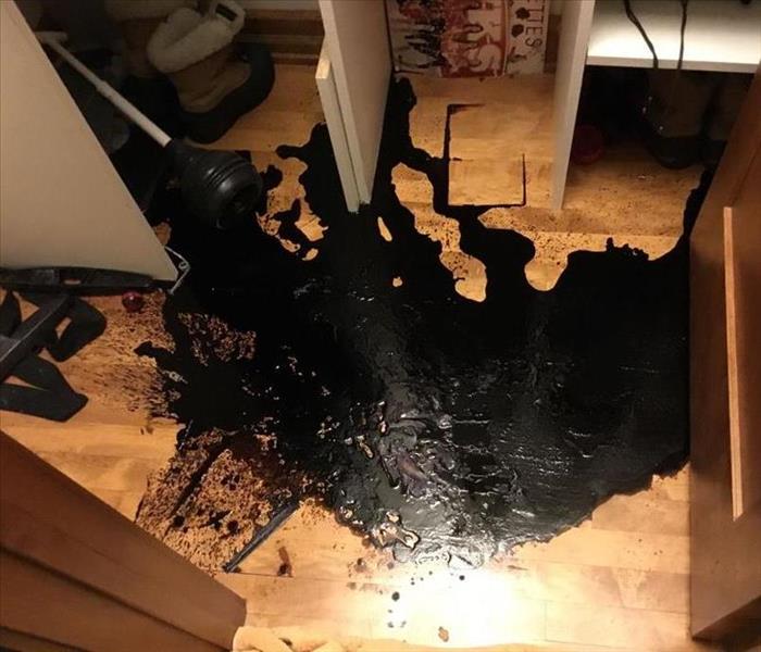 Black chemical spilled on hardwood floor in closet