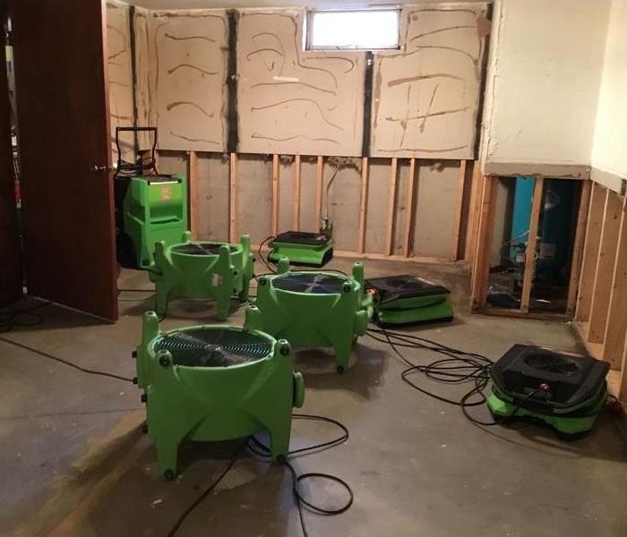 SERVPRO green equipment is placed in a basement to dry the flooring 