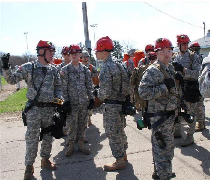 Several National guardsmen stand in red hats and in uniform  