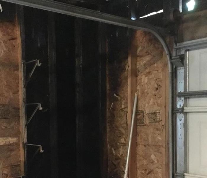 A corner of a garage that is black from a fire